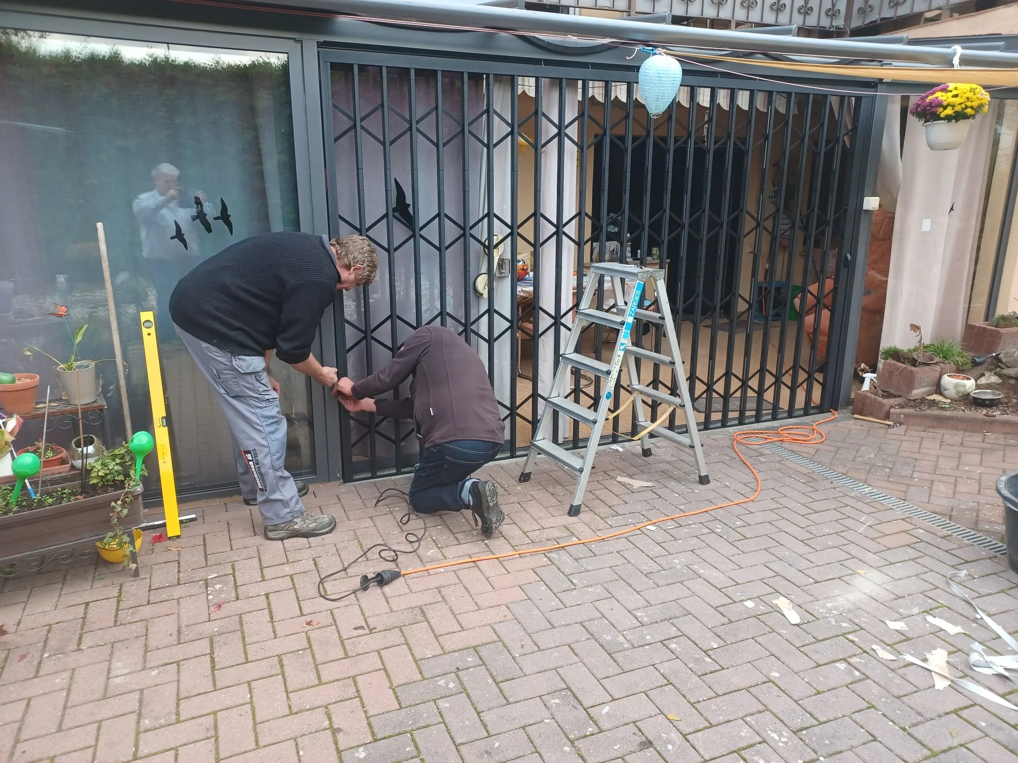 Werner Knoll Handwerker bei der Montage eines Scherengitters an der Terrasse